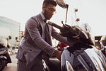 Businessman starting motorcycle on pavement