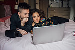 Couple using laptop on bed