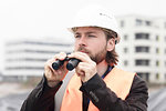 Mid adult male civil engineer holding binoculars on construction site