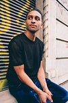 Young man waiting on window ledge of building