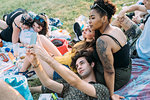 Group of friends relaxing, taking selfie at picnic in park