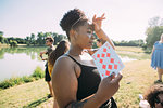 Young woman cooling off with playing card in park