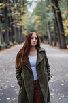 Young woman with long red hair in autumn park, portrait