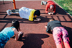 Calisthenics class at outdoor gym, young women and man practicing yoga position