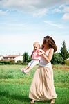 Mother carrying toddler daughter in rural landscape, Arezzo, Tuscany, Italy