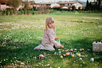 Cute girl sitting in field picking up easter eggs, portrait, Arezzo, Tuscany, Italy