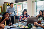 Young male and female business team sharing working lunch at cafe table