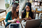 Young businesswomen remote working, looking at laptop in cafe