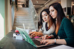 Young businesswomen using laptop at cafe table