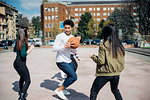 Young female and male adult friends playing basketball on city court