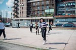 Young female and male adult friends fooling around on city basketball court