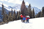 Mature couple and daughters taking a break while snowshoeing in snow covered mountain landscape, Styria, Tyrol, Austria