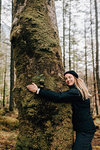 Woman hugging tree, Trossachs National Park, Canada
