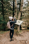 Woman photographing information board, Trossachs National Park, Canada