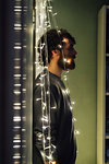 Bearded young man standing between string of decorative lights