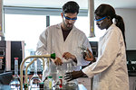 Young male and female scientists preparing experiment with sample bottles in laboratory