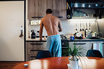 Mid adult man preparing breakfast at kitchen hob, rear view