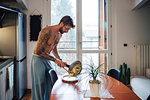 Mid adult man with tattoos serving omelette from frying pan