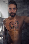 Mid adult man with tattooed chest in shower, portrait