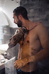 Mid adult man with tattoos taking a shower