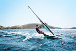 Young man windsurfing ocean waves, side view, Limnos, Khios, Greece