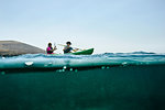 Teenage boy and mother sea kayaking, surface level side view, Limnos, Khios, Greece