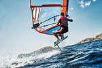 Young man mid air windsurfing ocean waves, side view, Limnos, Khios, Greece