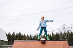 Boy standing on top of skateboard ramp pointing