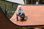 Boy preparing to sit down on skateboard on wooden skateboard ramp