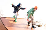 Boy chasing father on skateboard ramp, low angle view