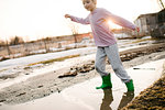 Boy playing in rural meltwater puddle