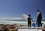 Boy surfer and father preparing surfboards on back of truck on beach, Cape Town, Western Cape, South Africa