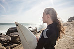 Young female surfer with flyaway hair looking out from beach rock, Cape Town, Western Cape, South Africa