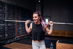Young woman lifting weight bar in gym