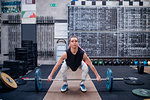 Young woman lifting barbell in gym