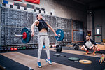 Young man watching woman lift barbell in gym