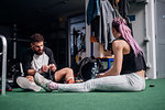 Woman talking to young man tying shoelace in gym