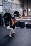 Young woman lifting barbell in gym