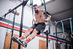 Young man balancing on gymnastic rings in gym