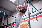 Young woman balancing on gymnastic rings in gym