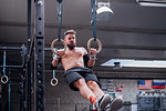 Young man balancing on gymnastic rings in gym