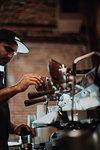 Barista using coffee machine in cafe, shallow focus side view
