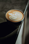 Fresh cup of latte with leaf pattern on edge of cafe counter, close up