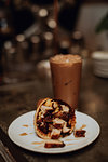 Waffle cone and glass of iced coffee on cafe table, shallow focus close up