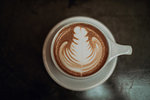 Cup of mocha topped with pattern on cafe table, low key overhead view