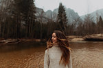 Young woman on riverbank shaking long brown hair, Yosemite Village, California, USA