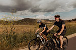 Young cycling couple cycling on rural road, Exeter, California, USA