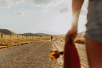 Young male skateboarder skateboarding on rural road, girlfriend watching, Exeter, California, USA