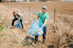 Couple picking up rubbish by field, Georgetown, Canada