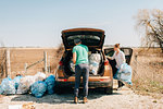 Couple putting rubbish bags into boot, Georgetown, Canada